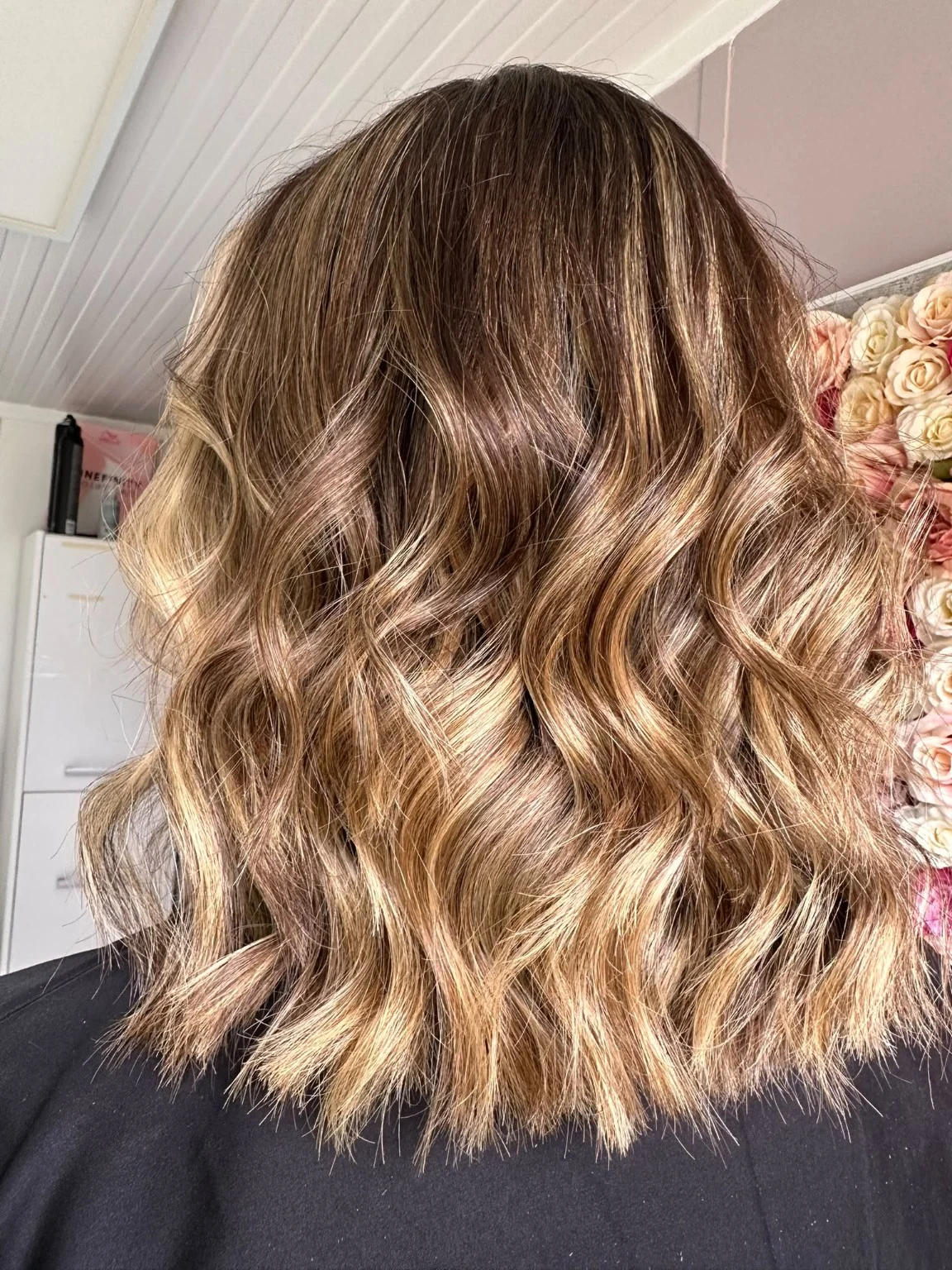 Warm brunette hair with caramel tones and a wavy finish